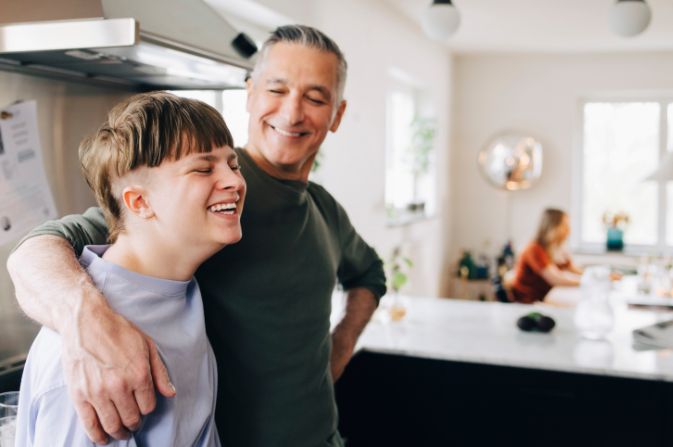 Teenager and man in a kitchen laughing