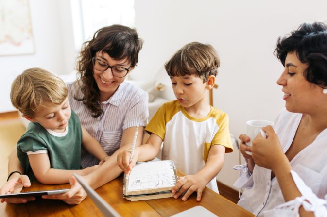 Two females with two boys drawing at a table